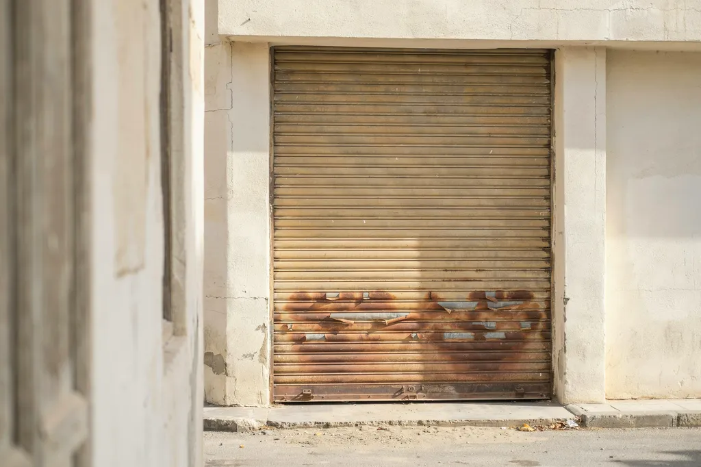 Old weathered metal shutter on a Kuwait shopfront before replacement